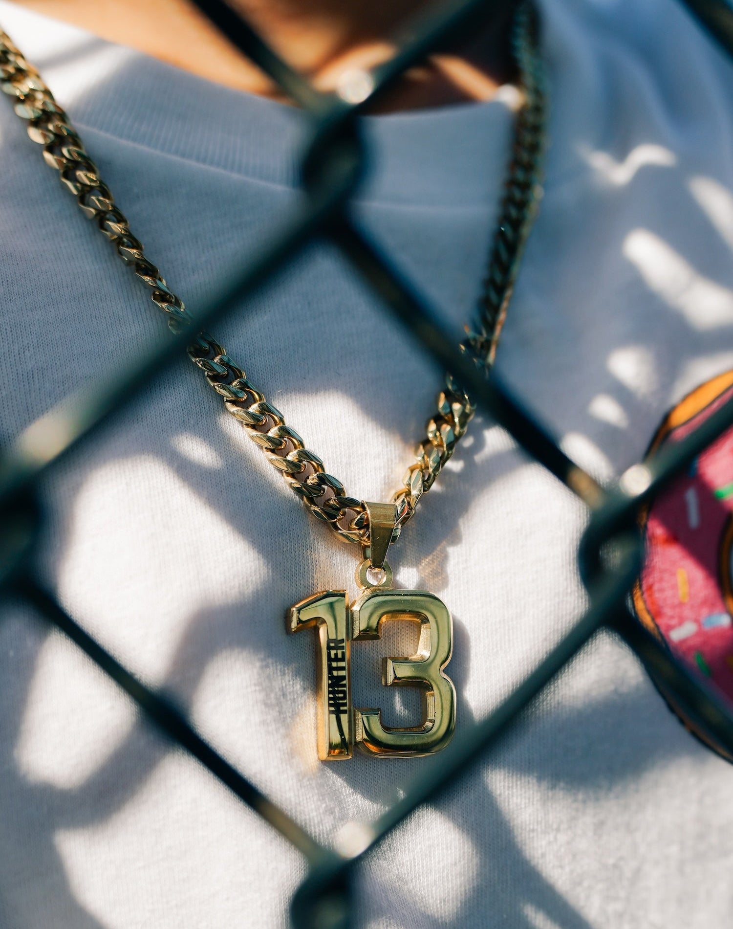 Gold necklace with a number 13 pendant on a textured surface.
